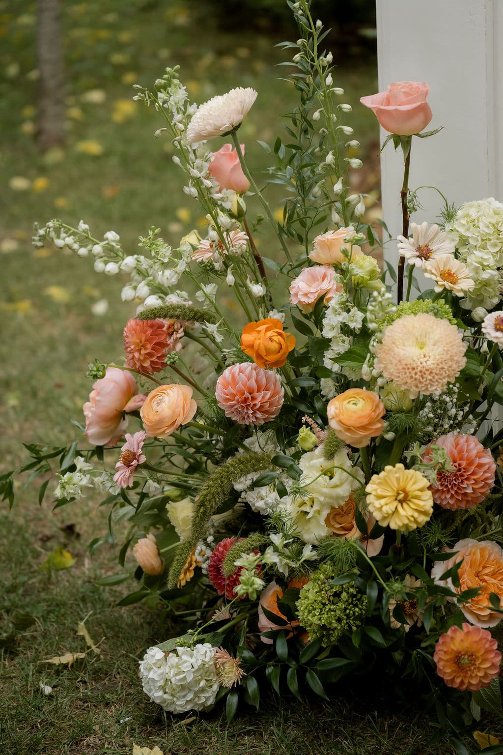 Close-up of peach roses, ranunculus, dahlias and zinnias in a ceremony arrangement