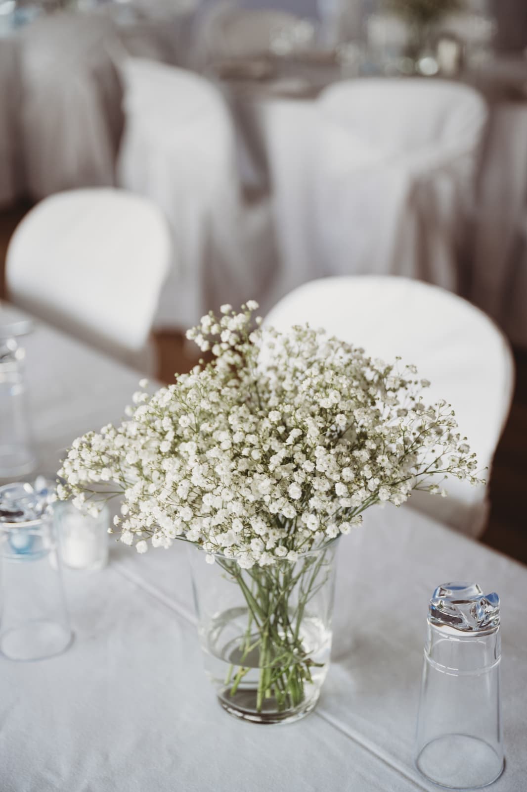 A full glass vase of baby's breath as the centerpiece of a white-set table