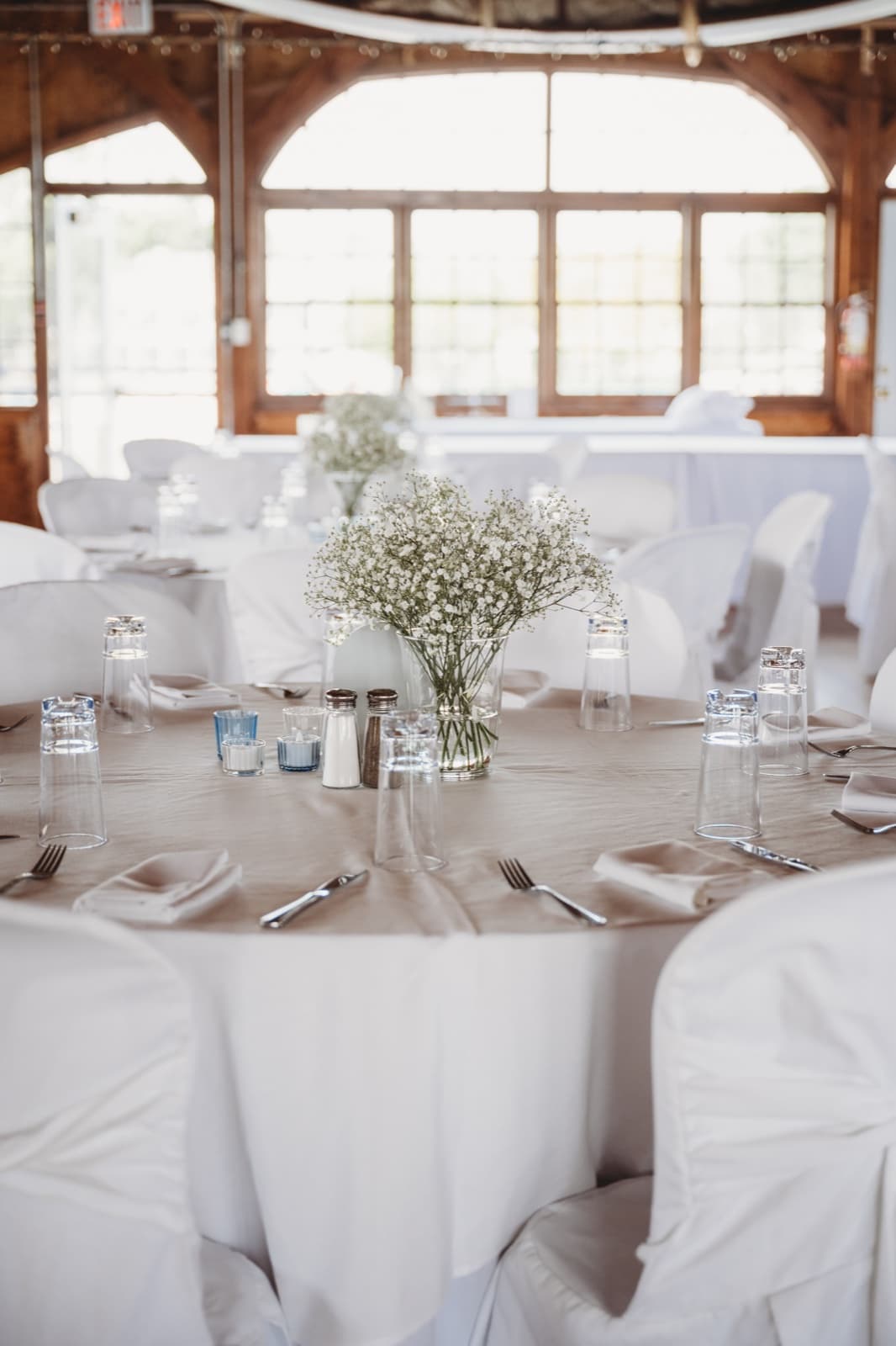 A baby's breath centerpiece at the middle of a set round table in a timber-frame hall