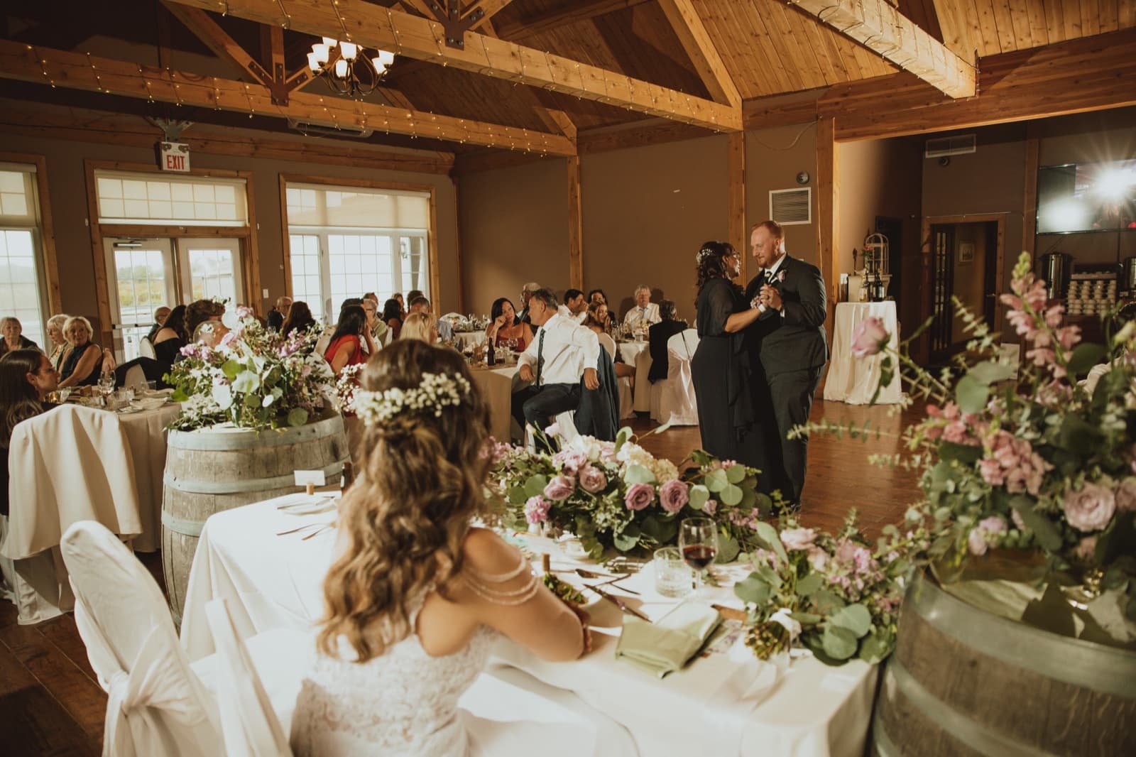 A first dance seen past a head table dressed with mauve roses and eucalyptus