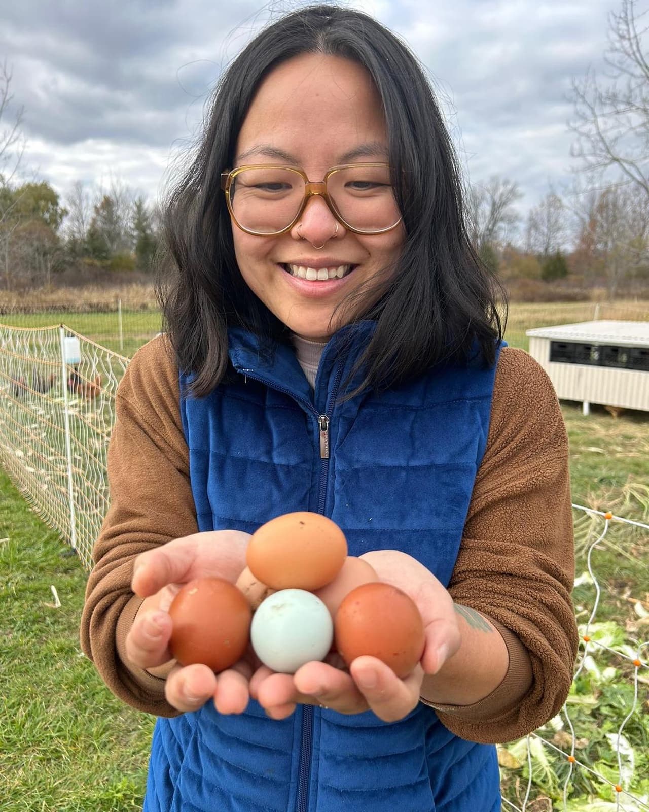 Yolanda Providence, co-founder of sunnmoon, holding fresh eggs beside the chicken run on the farm